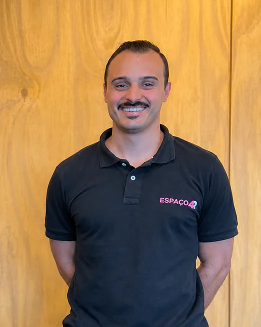 Henrique Santos, do Espaço4R, sorrindo em frente a uma parede de madeira
